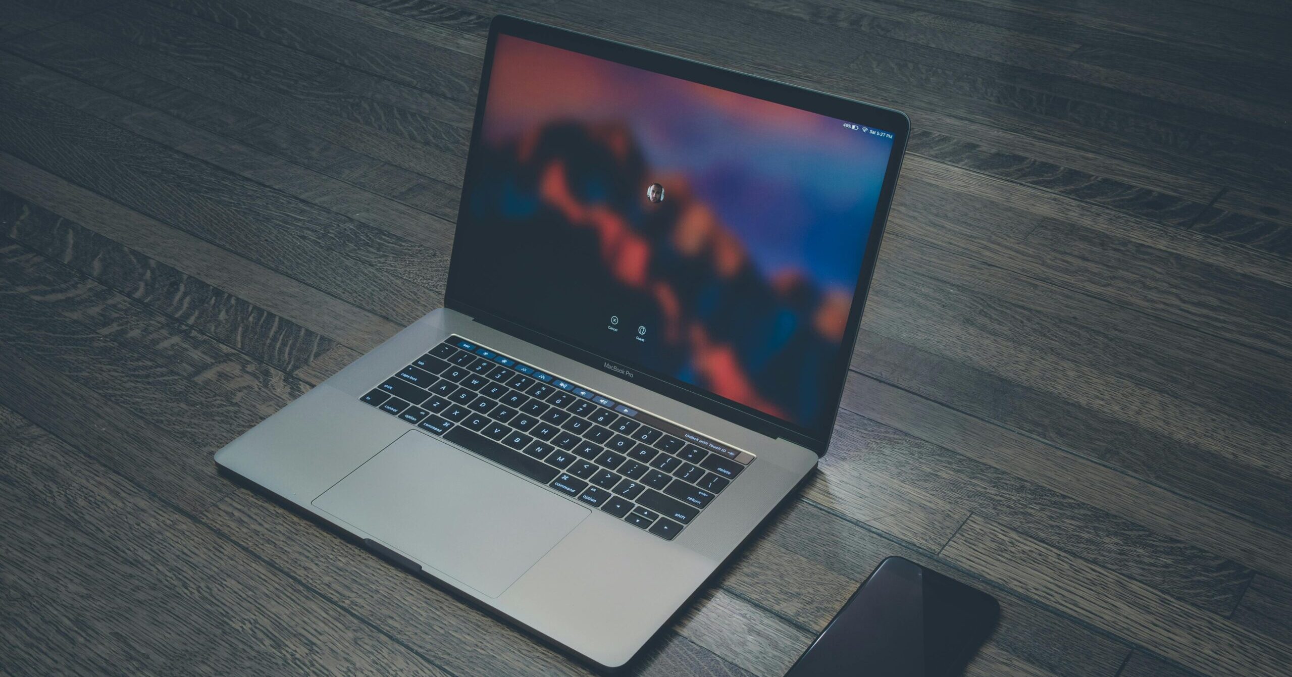 A sleek laptop and smartphone placed on wooden flooring, showcasing contemporary technology.